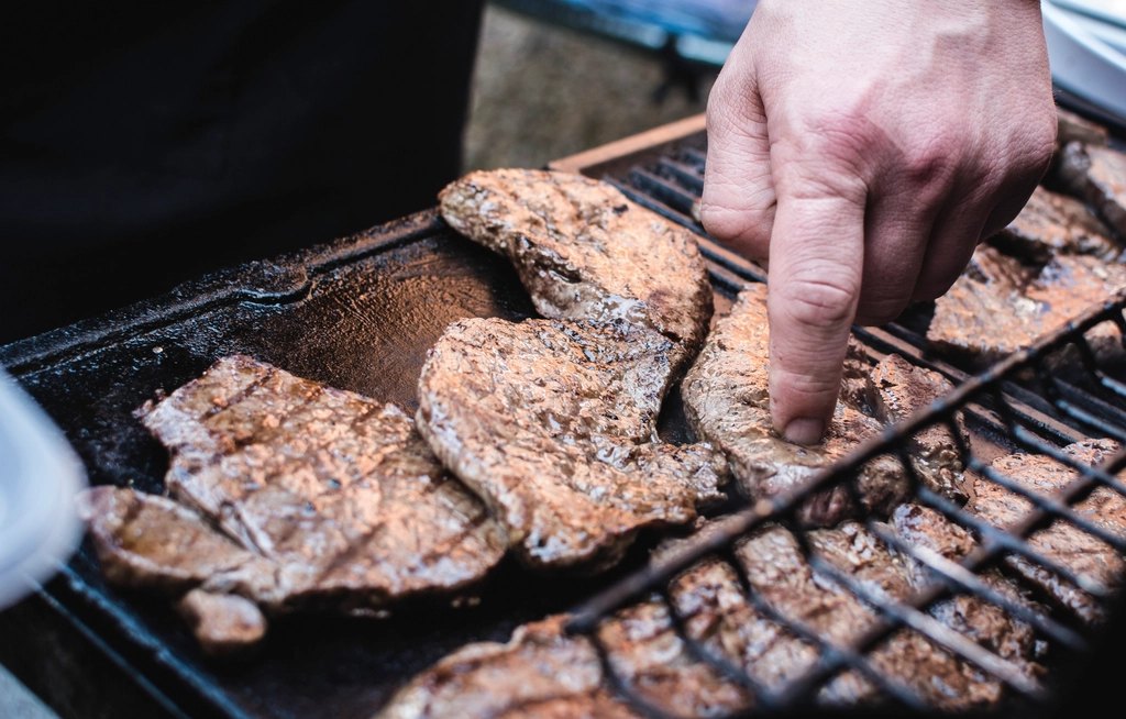 Mano dando vuelta carne en la parrilla